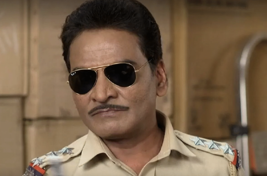 Daya Shankar Pandey as Chalu Pandey in his iconic police uniform, sharing a light moment with Dilip Joshi (Jethalal) on the TMKOC set.